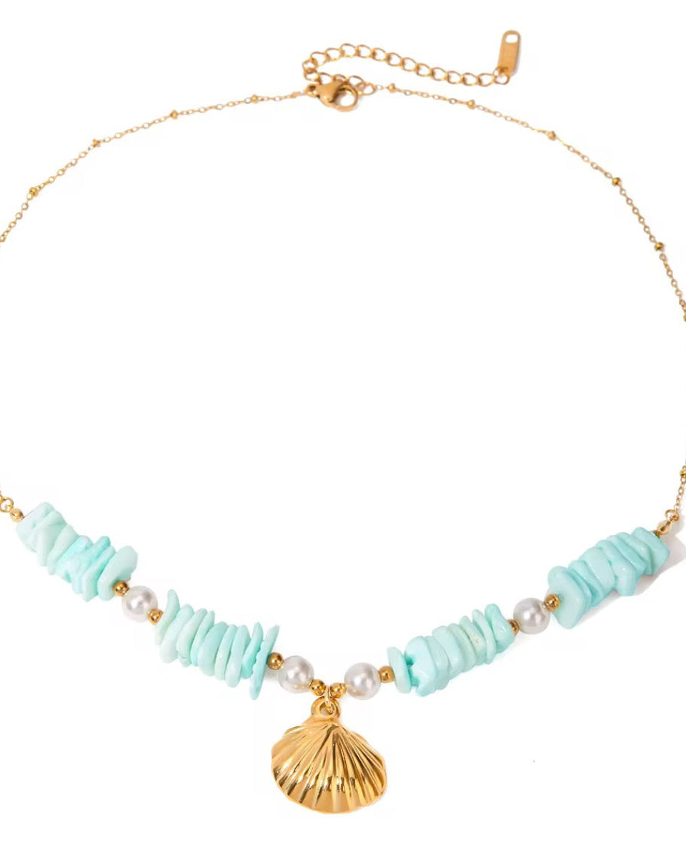A gold-colored necklace with a seashell pendant and aqua blue bead-like elements, displayed against a plain background.