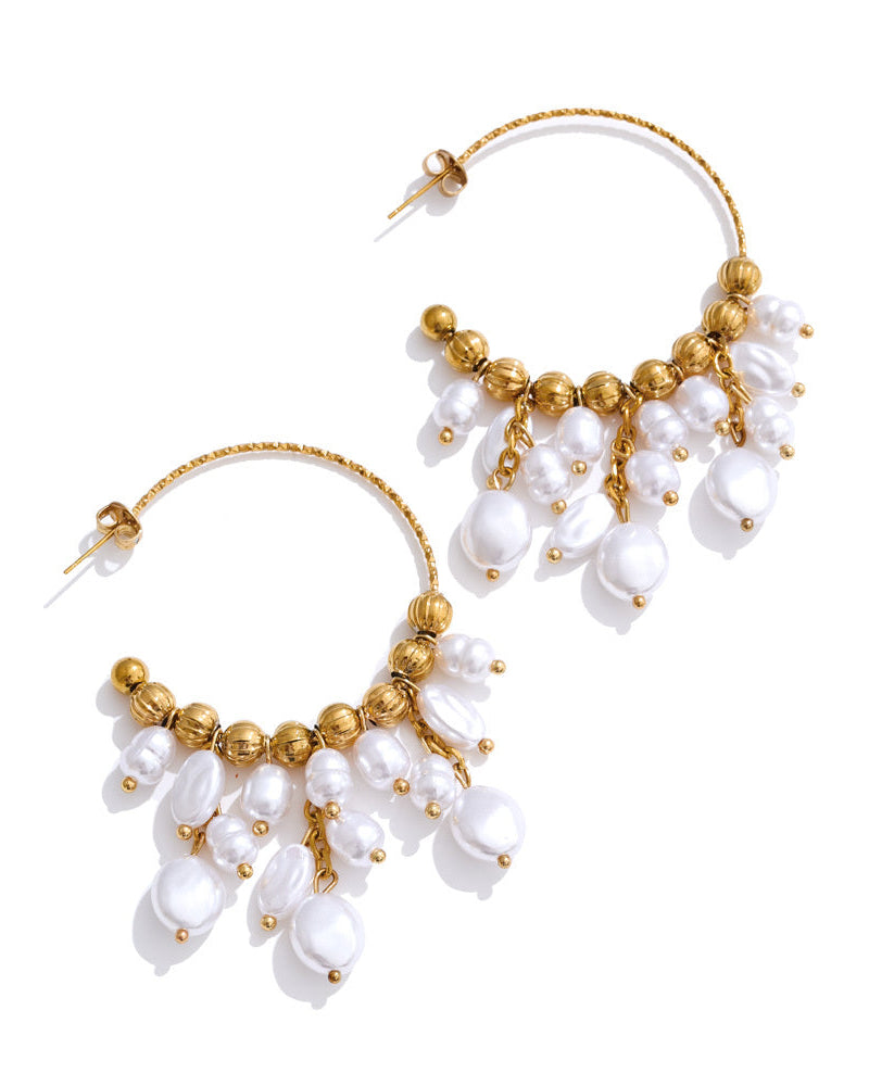 Pair of gold and pearl hoop earrings on a white background