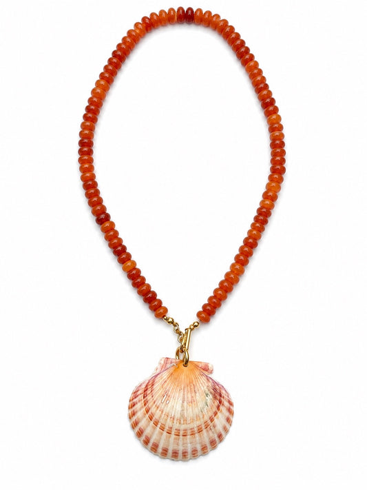 A beaded necklace made of round orange-brown beads with a large scallop shell pendant hanging from gold-tone hardware, shown on a plain white background.