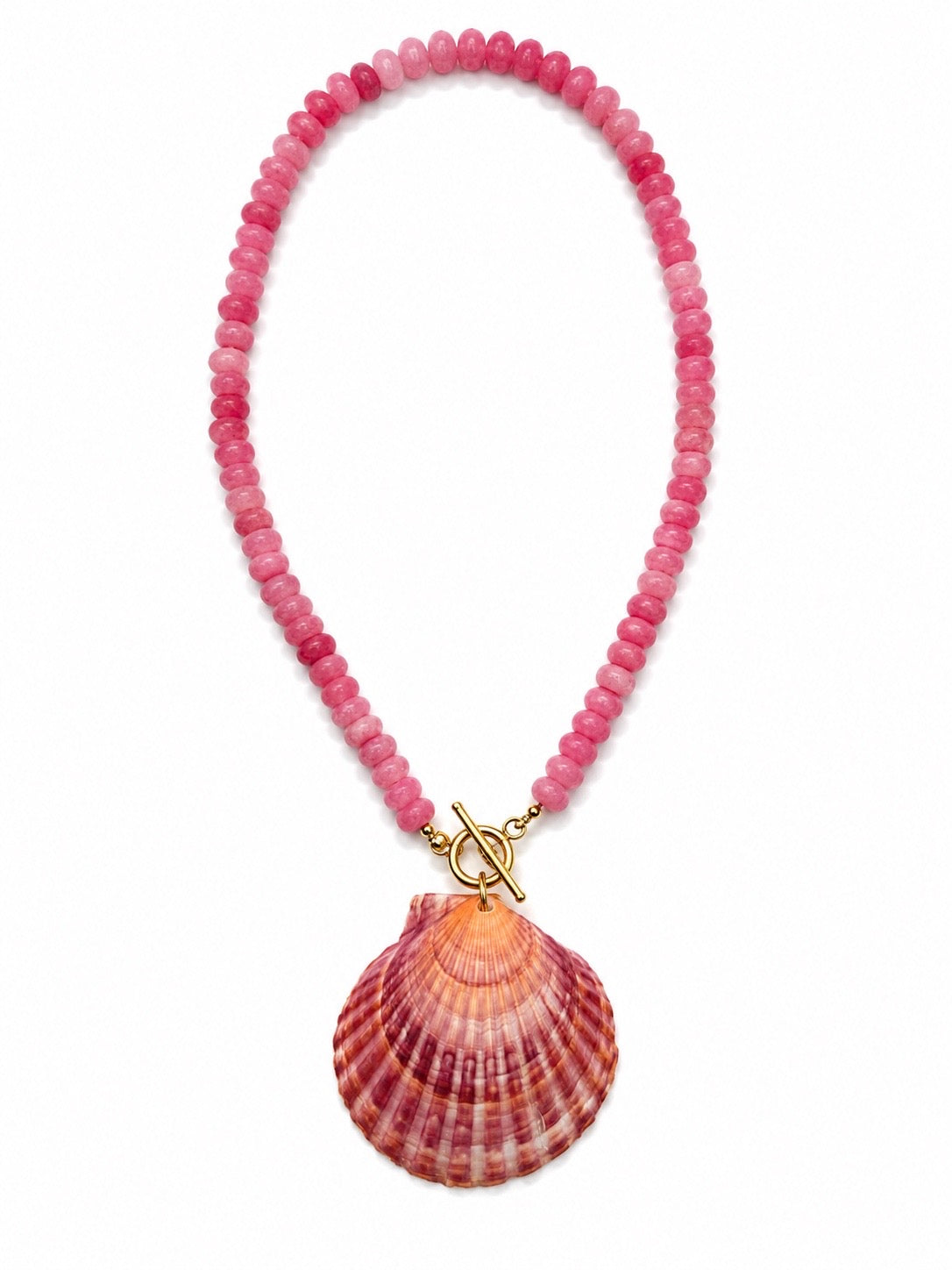 A pink beaded necklace featuring a large scallop shell pendant and a gold toggle clasp, displayed on a clean white background.
