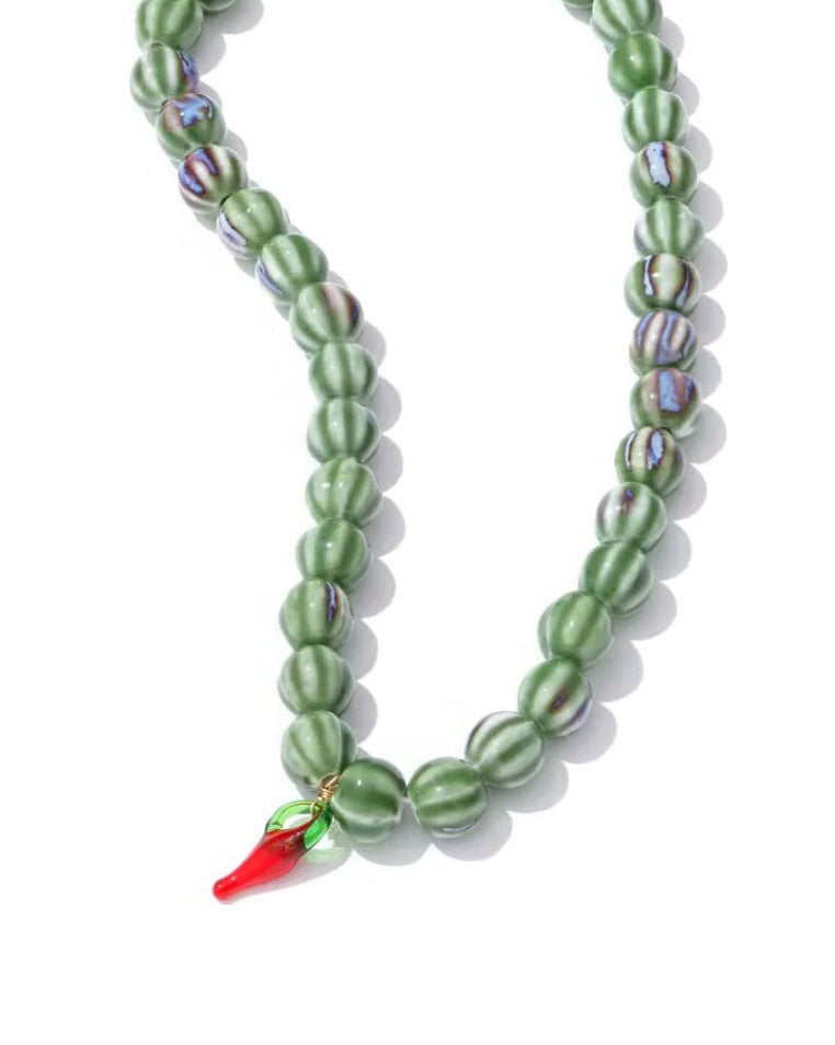 Green beaded necklace with a red accent on a white background